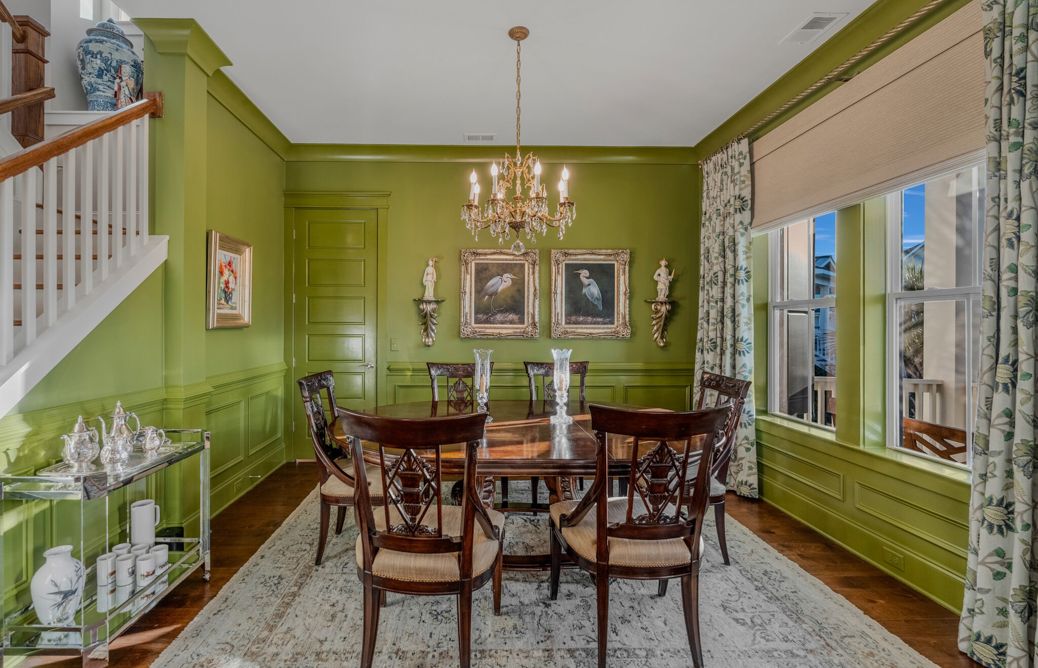 Garden-green dining room with paneled walls and chandelier